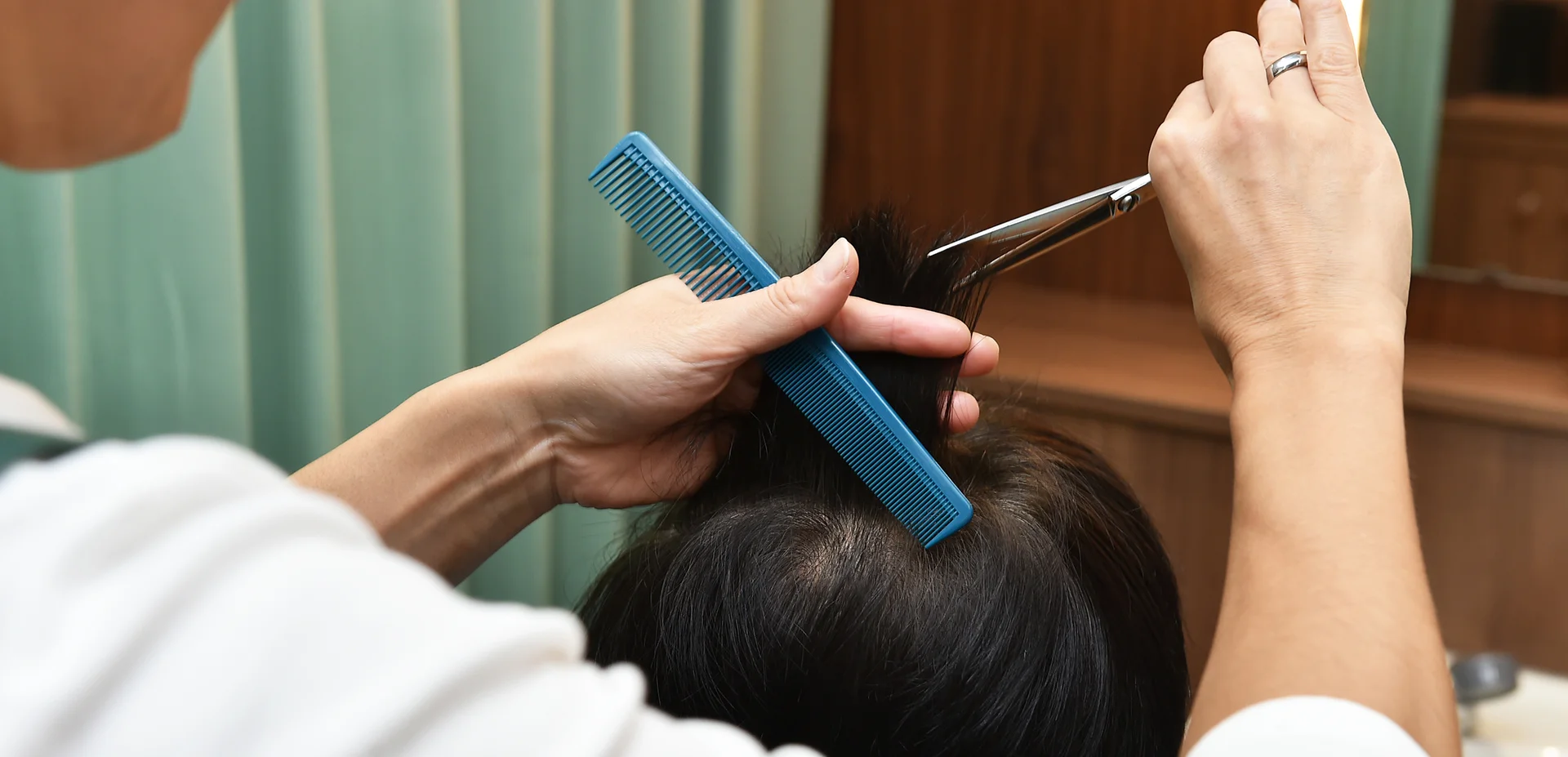鋏と櫛を使い髪を切り揃える理容師の手元