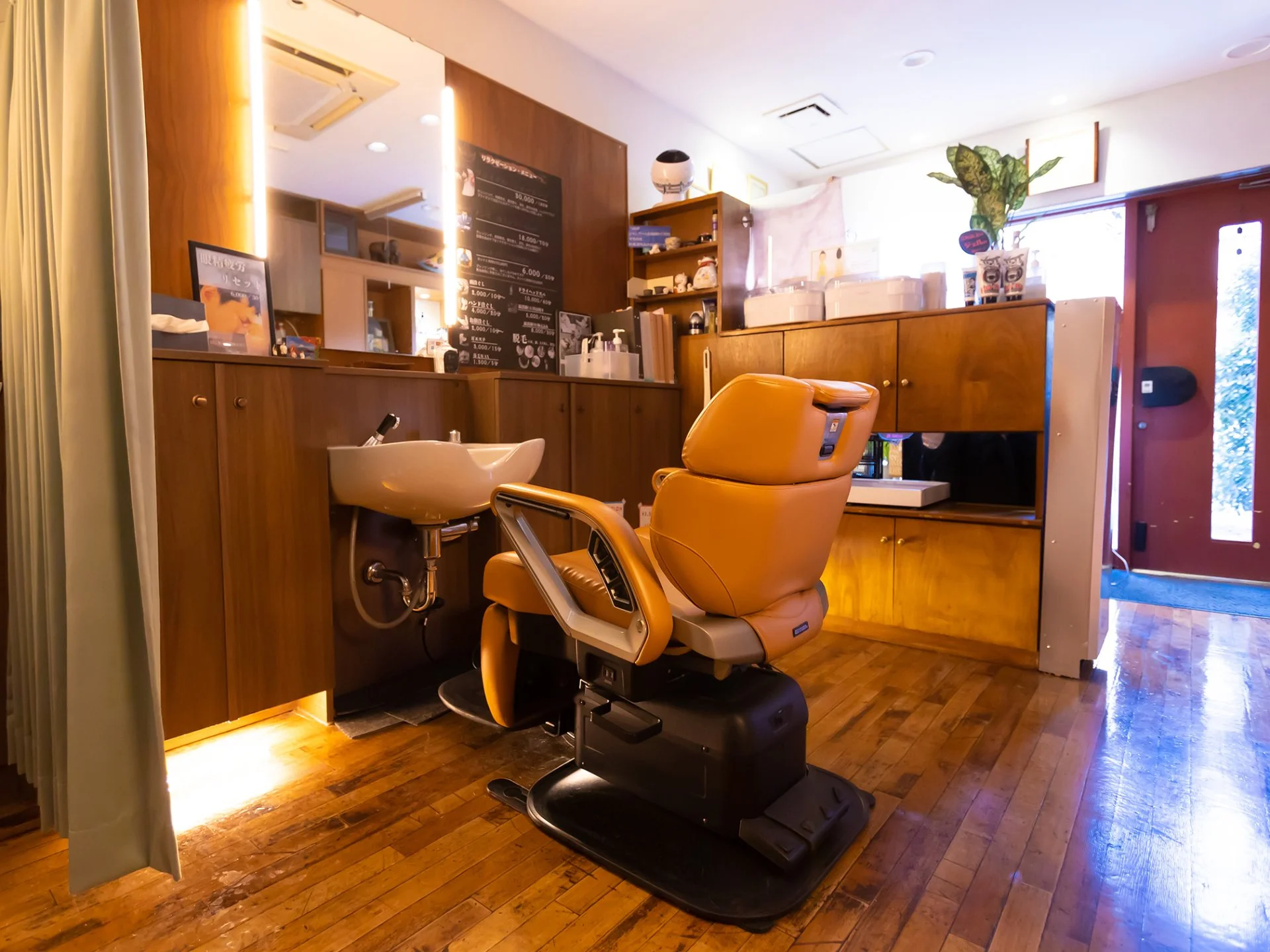 木目の床にオレンジ色の理容椅子とシャンプー台が並ぶ、ヘアサロンスイッチの店内